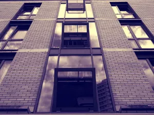 Low-angle view of a modern urban building facade with reflective glass windows and brick walls. jigsaw puzzle