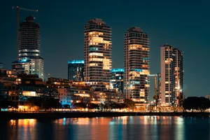 Night view of a vibrant urban skyline with skyscrapers reflecting on a river. jigsaw puzzle