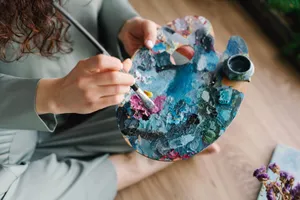 Close-up of hands painting on a colorful palette, showcasing creativity and artistry. jigsaw puzzle