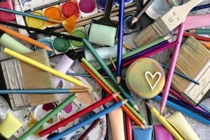A vibrant assortment of art supplies including paints, brushes, and pencils, featuring a heart motif. jigsaw puzzle