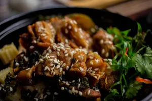 A savory Asian dish garnished with sesame seeds and fresh greens, perfectly captured in a close-up shot. jigsaw puzzle