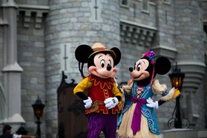 Mickey and Minnie Mouse in colorful costumes outside an iconic castle setting. jigsaw puzzle
