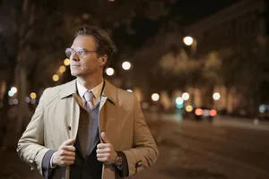 Confident adult male in formal wear standing on night street and holding collars of trench while looking away jigsaw puzzle