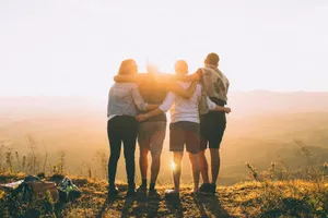 four person hands wrap around shoulders while looking at sunset jigsaw puzzle