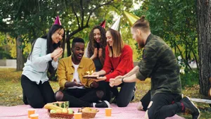 Group of friends enjoying a birthday celebration outdoors with cake and party hats. jigsaw puzzle