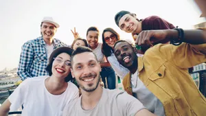 A diverse group of friends smiles while taking a selfie outdoors during the day. jigsaw puzzle