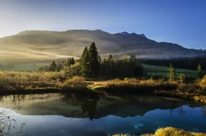 calm lake surrounded by trees near mountain range jigsaw puzzle