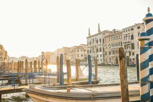 Boats docked in a sunny venetian canal with historic buildings. jigsaw puzzle
