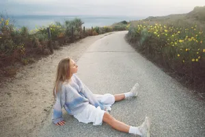 Young woman sitting on a road overlooking the ocean jigsaw puzzle
