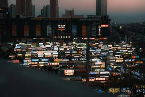 A dense cityscape illuminated by numerous glowing signs at dusk. jigsaw puzzle