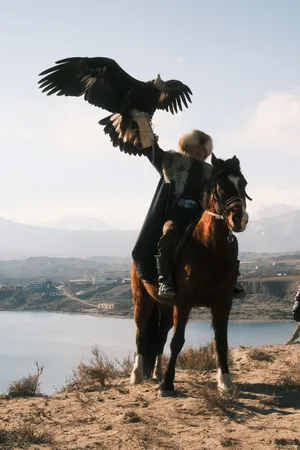 A traditional Kyrgyz falconer with an eagle and horse in a stunning mountain setting. jigsaw puzzle