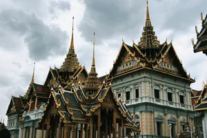 A beautiful view of the ornate rooftops of the Grand Palace in Bangkok, Thailand, under a cloudy sky. jigsaw puzzle