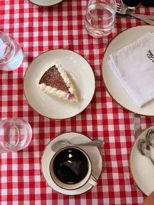 A slice of cake and a cup of coffee on a red checkered tablecloth, creating a cozy cafe vibe. jigsaw puzzle