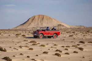 Explore the vast desert landscapes of Oued Ed-Dahab with a classic red 4x4 vehicle. jigsaw puzzle