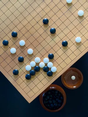 Aerial view of a Go board with black and white stones showcasing a strategic setup. jigsaw puzzle
