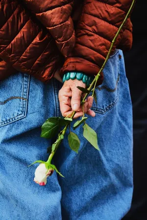 Elderly person holding a delicate white rose behind their back, symbolizing nostalgia. jigsaw puzzle