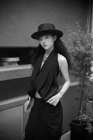Stylish woman in black hat and attire posing elegantly outdoors. jigsaw puzzle