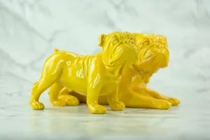 Close-up of yellow bulldog ornaments on a marble-like surface, showcasing glossy ceramic details. jigsaw puzzle