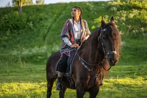 A woman on a black horse in a green meadow, enjoying a sunny day outdoors. jigsaw puzzle