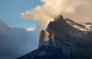 A majestic mountain peak in the Alps bathed in warm sunset light with clouds swirling around. jigsaw puzzle