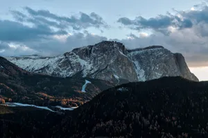 Stunning view of a mountainous landscape at dawn, showcasing snow-capped peaks under a dramatic sky. jigsaw puzzle