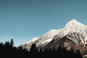 Breathtaking view of snow-capped mountains and forest at sunrise, ideal for adventure seekers. jigsaw puzzle
