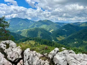 An expansive view of lush green forested mountains under a cloudy sky. jigsaw puzzle
