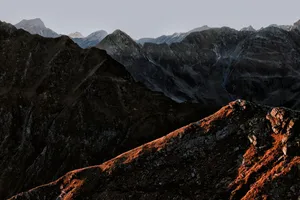 Stunning view of a mountain range at sunset with dramatic lighting and rocky terrain. jigsaw puzzle