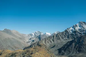 Stunning high-altitude view of rocky mountains with clear blue sky backdrop, ideal for nature lovers. jigsaw puzzle