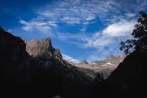 Scenery view of rough mountains with dry surface and growing trees under bright sky in summer jigsaw puzzle