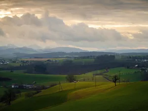 Breathtaking view of rolling hills and fields under a dramatic sunset sky. jigsaw puzzle