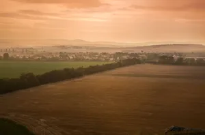 Aerial view of a picturesque countryside with fields and distant hills under a warm dawn sky. jigsaw puzzle