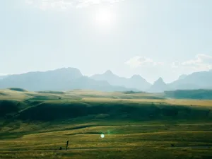 Peaceful rolling hills with a hazy mountain range under a bright sky, ideal for nature lovers. jigsaw puzzle