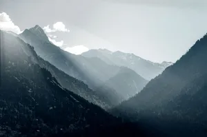 Breathtaking view of sunrays piercing through the misty mountains in Pahalgam, capturing the essence of serene nature. jigsaw puzzle