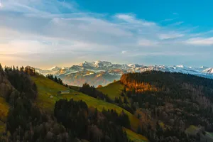Breathtaking view of green hills and snowy mountains under a vibrant sky. jigsaw puzzle