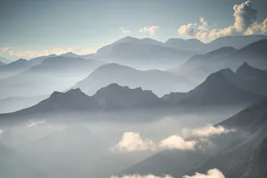 Breathtaking view of a mist-covered mountain range under a clear blue sky at dawn. jigsaw puzzle