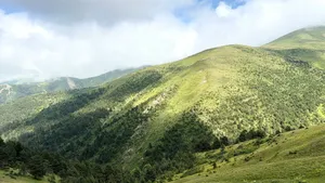Lush green mountain landscape under a partly cloudy sky, showcasing natural beauty and tranquility. jigsaw puzzle