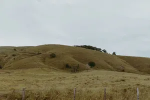 Expansive rural landscape featuring rolling hills and a weathered fence under a cloudy sky. jigsaw puzzle