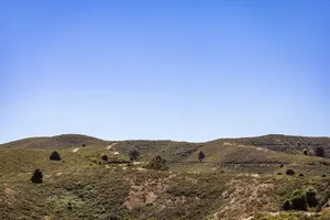 A serene landscape showcasing rolling green hills beneath a bright blue sky, perfect for nature lovers. jigsaw puzzle