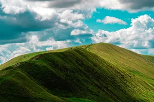 A breathtaking aerial view of lush green hills under a dynamic sky with clouds, capturing nature's beauty. jigsaw puzzle