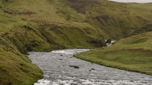 Peaceful river winding through lush green hills under a cloudy sky. jigsaw puzzle