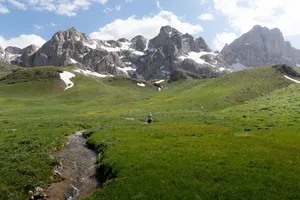 A serene mountain landscape featuring a stream and lush greenery under a bright summer sky. jigsaw puzzle