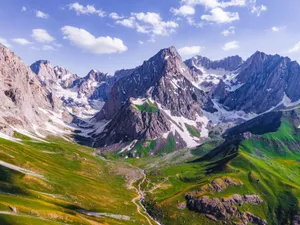 Stunning view of a snow-capped mountain range with vibrant green valleys. jigsaw puzzle