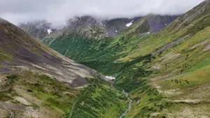 Breathtaking view of lush green mountain valley with cloud-covered peaks. jigsaw puzzle