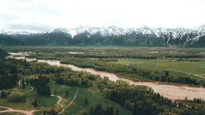 Breathtaking aerial shot of snow-capped mountains with lush green valley below. jigsaw puzzle