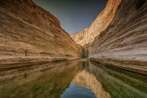 Explore the breathtaking cliffs and serene water reflections in Israel's desert canyon. jigsaw puzzle
