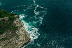 A breathtaking aerial view of rugged cliffs meeting the vibrant ocean waves. jigsaw puzzle