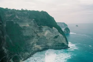 A stunning aerial view of Bali's coastal cliffs, showcasing the dramatic sea and lush vegetation. jigsaw puzzle