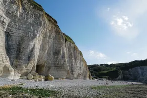 Stunning seaside cliffs with eroded rock formations and small beachgoers on a clear day. jigsaw puzzle
