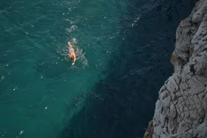 A swimmer in the blue sea by rocky cliffs at Polignano a Mare, Italy. jigsaw puzzle